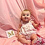 baby, infant, child, pink_backdrop, romper, sitting, smile, face, confetti, shredded_paper, card, letter_m, toes, legs, studio_shot, portrait, cheeks, decor, fabric, cute