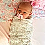 baby, infant, pacifier, blanket, floral_pattern, bedspread, pink, white, wrapped, lying_down, face, head, skin, newborn, child, soft_texture, indoor, cute, peaceful, portrait