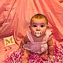 baby, infant, pacifier, pink_backdrop, fabric_drape, sitting, dress, bare_feet, big_eyes, adorable, face, cheeks, ears, toy_block, letter_m, shredded_paper, confetti, crib_slats, portrait, indoor