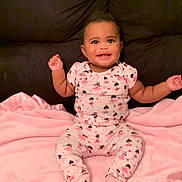 Journey is registered to the contest to win money with this photo: baby, child, smile, pink, blanket, couch, sitting, clothing, happy, face, infant, indoors, cute, portrait, pajamas, raised_hands, soft_texture, young_child, cheerful, cozy