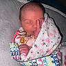 Delilah is registered to the contest to win money with this photo: newborn, baby, sleeping, infant, face, pacifier, blanket, floral_blanket, swaddled, cozy, portrait, indoors, bed, cushion, hand, finger, closed_eyes, pink, colorful, photography