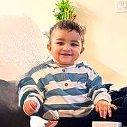 Augustine is registered to the contest to win money with this photo: toddler, child, smile, striped_hoodie, couch, plant, indoor, portrait, happy, cozy, home, furniture, painting, wall, person, seated, casual, young_child, cute, living_room