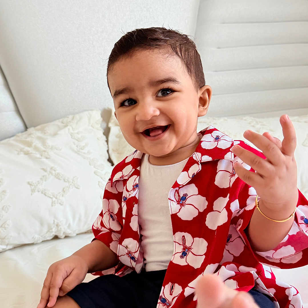 Augustine joined the competition — help win amazing prizes! toddler, child, smiling, foot, bed, white_bed, floral_shirt, red_shirt, navy_shorts, happy, indoor, portrait, cute, baby, person, sitting, hand, head, face, home