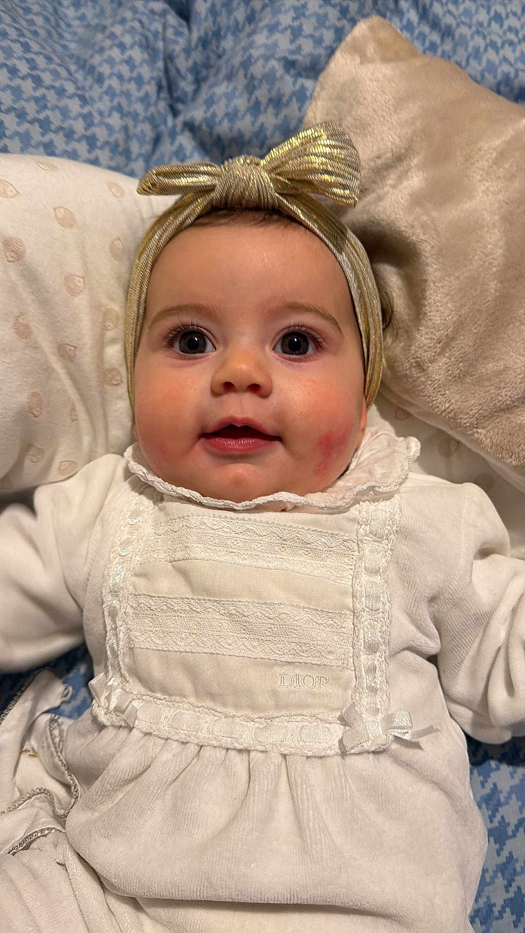 Chiara participe au concours pour gagner de l'argent avec cette photo : baby, infant, child, face, headband, bow, big_eyes, cheeks, smile, onesie, white_clothing, lace, pillow, blanket, bedding, lying_down, portrait, indoor, close_up, soft_lighting