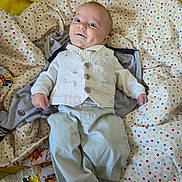 Eli is registered to the contest to win money with this photo: baby, infant, smiling, vest, pants, blanket, polka_dot, dimple, lying_down, cute, child, happy, face, clothing, fabric, soft, comfort, indoor, person, portrait