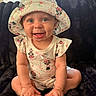 baby, child, infant, smiling, happy, portrait, sitting, sunhat, floral_clothing, disney_character, minnie_mouse, onesie, indoor, blanket, couch, window, natural_light, close_up, bare_feet, photography