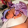 newborn, baby, purple_dress, headband, sleeping, blanket, flower, doll, soft_texture, indoors, infant, cute, peaceful, portrait, child, toddler, skin, hand, foot, decor