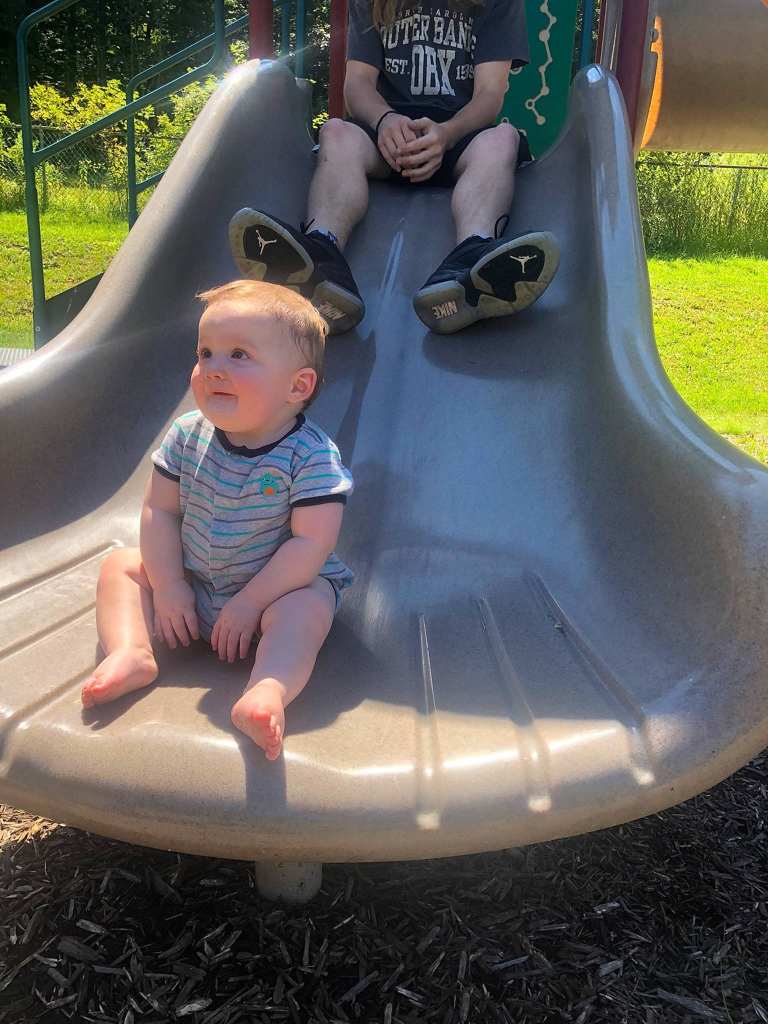 Bowen is registered to the contest to win money with this photo: baby, baby_toddler_clothing, child, chute, city, comfort, fun, grass, green, leisure, outdoor_play_equipment, person, photograph, plant, play, playground, playground_slide, recreation, sitting, smile