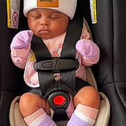 Khalila joined the competition — help win amazing prizes! baby, infant, car_seat, hat, pom_poms, sleeping, socks, mittens, safety_harness, black, pink_clothing, closeup, cute, child, newborn, seat_belt, soft, cozy, indoor, peaceful