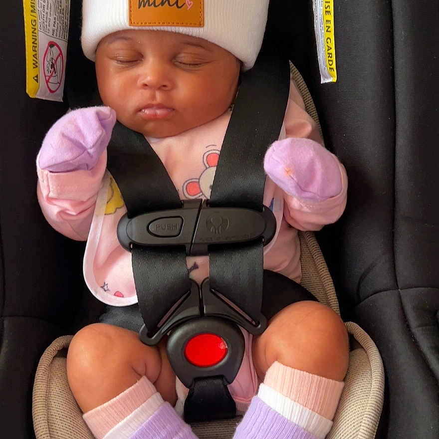 Khalila joined the competition — help win amazing prizes! baby, black, car_seat, child, closeup, cozy, cute, hat, indoor, infant, mittens, newborn, peaceful, pink_clothing, pom_poms, safety_harness, seat_belt, sleeping, socks, soft