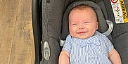 Eden a rejoint le concours — aidez-le/la à gagner de superbes lots ! baby, car_seat, smile, infant, striped_shirt, blue_and_white, black_pants, floor, wooden_floor, footwear, sandals, indoor, happy, person, child, seat, seatbelt, cabin, cute, casual