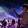 Nino a rejoint le concours — aidez-le/la à gagner de superbes lots ! child, crowd, night, outdoor, event, people, spray, light, sky, person, shoulders, curious, blue, glow, motion, excited, young, festival, celebration, silhouette