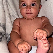 Elijah is registered to the contest to win money with this photo: baby, infant, bare_chest, diaper, holding_feet, wide_eyes, curious, plush_blanket, soft_texture, cute, child, portrait, skin, hand, foot, fingers, toes, expression, sitting, indoors