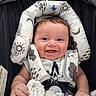 baby, smile, infant, car_seat, blanket, head_support, clothing, happy, child, cute, face, hand, fabric, pattern, comfort, seatbelt, indoors, portrait, skin, young_child