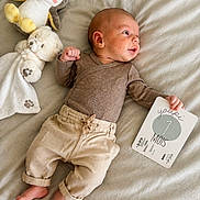 Tyméo participe au concours pour gagner de l'argent avec cette photo : baby, infant, plush_toy, penguin_toy, teddy_bear, milestone_card, 7_months, bed, blanket, clothing, pants, long_sleeve, bare_feet, cute, lying_down, portrait, indoor, soft_lighting, child, smile