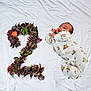 baby, infant, onesie, lying_down, white_sheet, number_two, leaves, berries, flower, nature, cute, small, child, portrait, closeup, soft, sleepwear, indoors, expression, resting