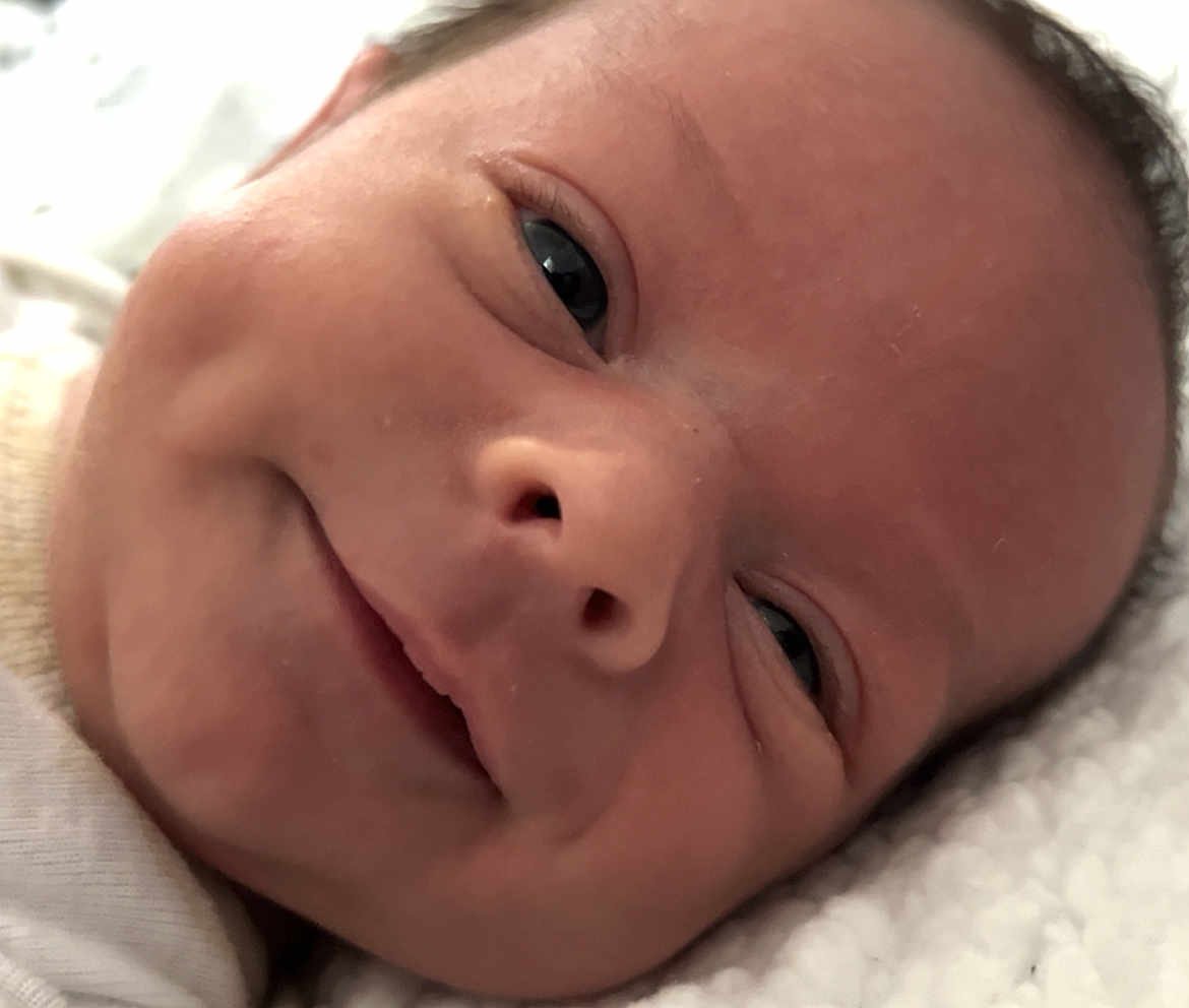 Leon is registered to the contest to win money with this photo: baby, close_up, smile, face, skin, infant, dimples, newborn, cute, portrait, child, soft_light, blanket, lying_down, cozy, expression, head, human, happy, sleepwear