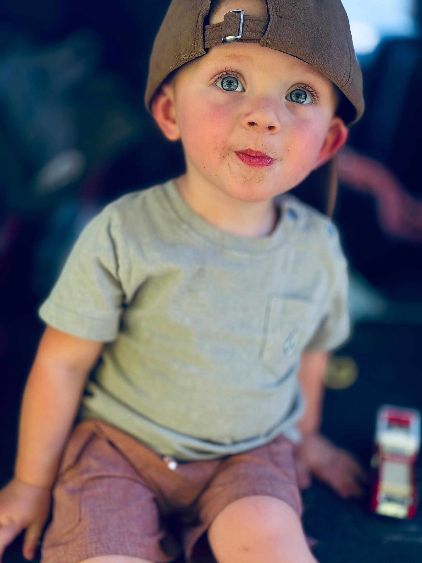 Logan joined the competition — help win amazing prizes! toddler, child, boy, cap, blue_eyes, curious, casual_clothing, shorts, tshirt, toy, fire_truck, sitting, portrait, indoor, closeup, face, expression, natural_light, blurred_background, cute