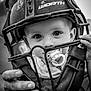 Logan joined the competition — help win amazing prizes! baby, child, pacifier, helmet, catchers_mask, black_and_white, face, eyes, hands, person, sports_equipment, closeup, portrait, curious, innocence, outdoor, expression, headgear, baby_face, protective_gear