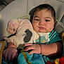 baby, infant, child, face, hand, blanket, plush_toy, clothing, sitting, indoors, portrait, cozy, cute, comfort, soft_toy, colorful, young, resting, expression, closeup