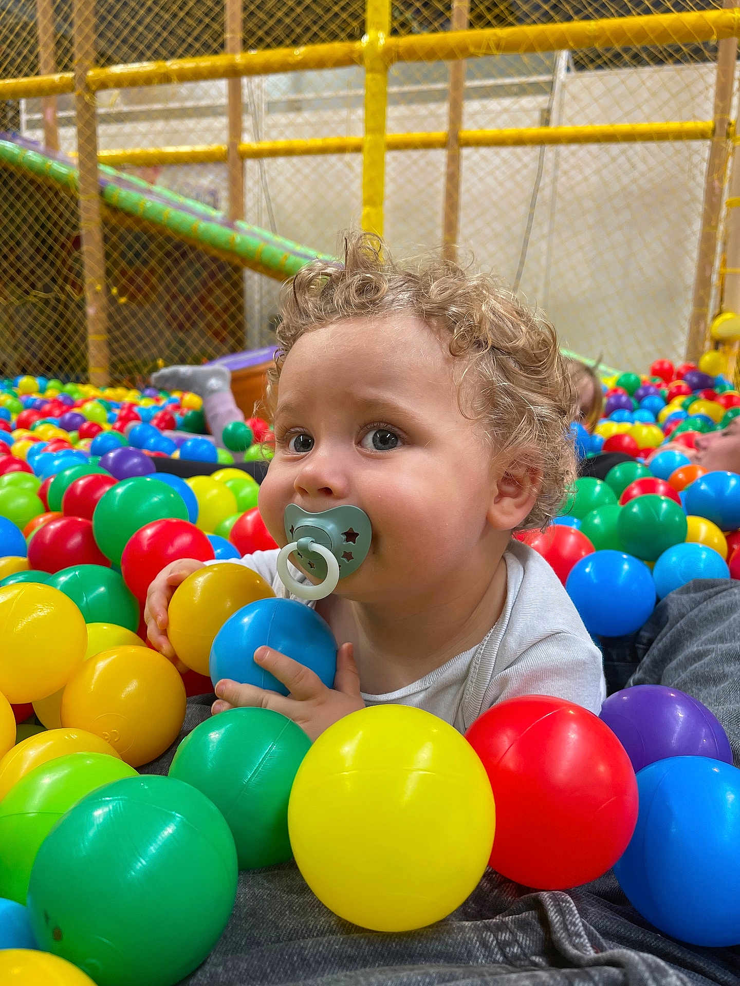 Malone participe au concours pour gagner de l'argent avec cette photo : toddler, child, pacifier, ball_pit, colorful_balls, curly_hair, indoor_playground, play_area, baby, bright_colors, smiling, fun, cute, young_child, clothing, hand, face, person, play, happy