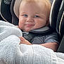 baby, child, car_seat, seatbelt, blue_eyes, blond_hair, towel, smile, cute, infant, striped_clothing, safety, indoors, closeup, face, headrest, comfort, car_interior, soft_texture, happy