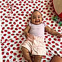 baby, smiling, infant, calvin_klein, pink_shorts, purple_top, strawberry_pattern, bed_sheet, lying_down, toy, pacifier, plush_toy, happy, cute, child, indoors, person, skin, foot, hand
