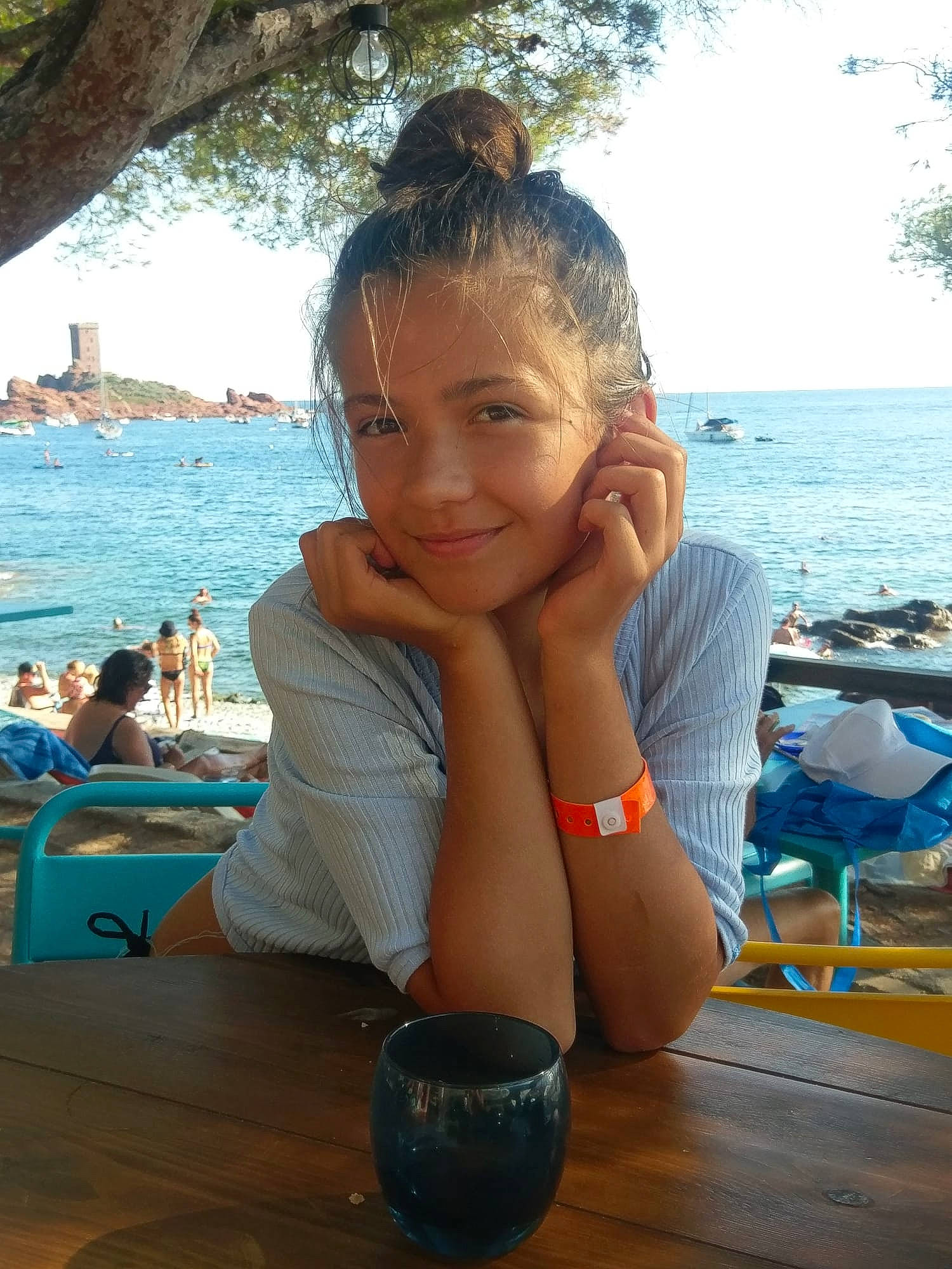 Eugénie participe au concours pour gagner de l'argent avec cette photo : beach, blue, blurred, cup, event, eyewear, fun, happy, joy, lake, leisure, person, recreation, sitting, sky, smile, t_shirt, table, tableware, thumb