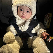 Leon joined the competition — help win amazing prizes! baby, child, car_seat, bear_costume, fluffy, cute, infant, safety_harness, black_background, indoors, portrait, adorable, young_child, soft_texture, warm_clothing, seatbelt, small_hands, wide_eyes, hood, cozy