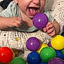 baby, blue_ball, child, closeup, colorful_balls, cushion, cute, fun, green_ball, happy, indoor, infant, joy, patterned_cushion, plastic_balls, playing, purple_ball, red_ball, smiling, yellow_ball