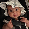 baby, infant, child, portrait, car_seat, floral_hat, hat, wide_eyes, face, hands, sitting, harness, safety, vehicle, indoors, close_up, fashion, floral_pattern, adorable, photograph