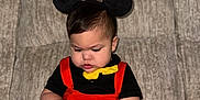 Liam is registered to the contest to win money with this photo: baby, black_shirt, child, chubby, costume, couch, cute, face, focused, furniture, hair, hands, indoors, mickey_mouse, mouse_ears, red_overalls, remote_control, sitting, toddler, yellow_bow_tie
