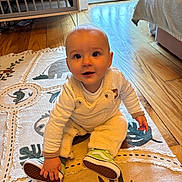 Léandro participe au concours pour gagner de l'argent avec cette photo : baby, child, infant, sitting, rug, floor, wooden_floor, overalls, sneakers, green_shoes, indoor, crib, curious, cute, person, home, patterned_rug, clothing, hand, face
