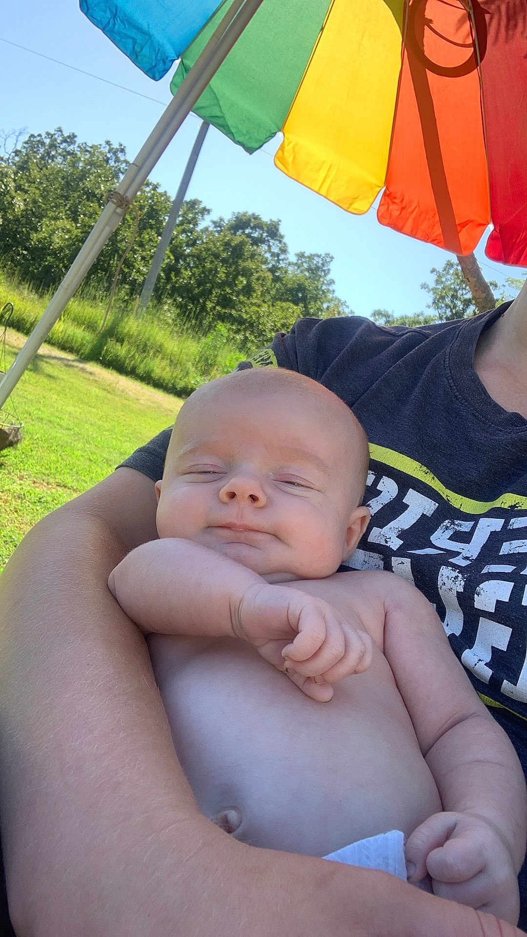 Bodhi joined the competition — help win amazing prizes! baby, infant, arm, person, umbrella, rainbow, outdoor, nature, greenery, sunlight, smile, shirt, tshirt, skin, hand, holding, relaxing, daylight, portrait, peaceful