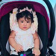 Doutzen joined the competition — help win amazing prizes! baby, child, stroller, toy, bow, hair, face, hand, clothing, sitting, seat_belt, infant, cute, indoor, portrait, colorful, pink, black, blue, expression