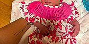Josie is registered to the contest to win money with this photo: baby, newborn, infant, pink_bow, headband, dress, patterned_clothing, tattoo, arm, blanket, soft_texture, wooden_floor, person, child, cute, resting, indoor, holding, hand, skin