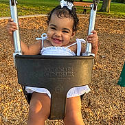 Brianna joined the competition — help win amazing prizes! toddler, child, swing, playground, smile, happy, outdoor, park, woodchips, dress, bow, sunlight, grass, bench, tree, person, summer, daylight, cute, play