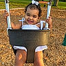 toddler, child, swing, playground, smile, happy, outdoor, park, woodchips, dress, bow, sunlight, grass, bench, tree, person, summer, daylight, cute, play