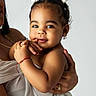 Brianna joined the competition — help win amazing prizes! toddler, child, baby, smiling, portrait, white_bow, curly_hair, wrapped_in_cloth, adult_hand, gold_ring, red_bracelet, soft_lighting, studio_background, cute, happy, close_up, skin, face, holding, affection