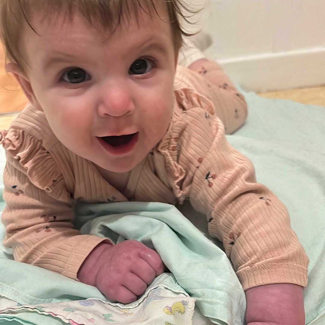 Albane participe au concours pour gagner de l'argent avec cette photo : baby, blanket, child, clothing, curious, cute, expression, eyes, face, floor, hair, hand, indoor, infant, lying_down, pajamas, person, skin, smiling, toddler