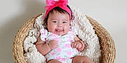 Penelope is registered to the contest to win money with this photo: baby, infant, smiling, basket, blanket, headband, pink_bow, floral_outfit, cute, happy, indoors, soft_texture, child, portrait, newborn, cozy, resting, skin, feet, hands