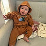 baby, blanket, brown_clothing, casual, child, couch, cozy, cute, fabric, face, foot, hand, happy, hoodie, indoor, infant, person, seated, smile, sofa