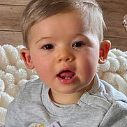 Milo a rejoint le concours — aidez-le/la à gagner de superbes lots ! baby, blanket, child, closeup, cozy, ears, eyes, face, indoor, light_hair, open_mouth, portrait, rosy_cheeks, sitting, soft_texture, sticker, sweater, teeth, toddler, wooden_wall