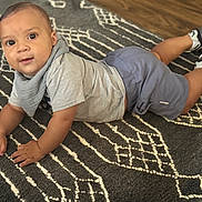 Uriah joined the competition — help win amazing prizes! baby, child, infant, floor, rug, pattern, clothing, shorts, shirt, socks, sneakers, indoor, person, cute, looking_at_camera, hands, head, eyes, skin, expression