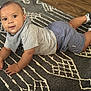 baby, child, infant, floor, rug, pattern, clothing, shorts, shirt, socks, sneakers, indoor, person, cute, looking_at_camera, hands, head, eyes, skin, expression