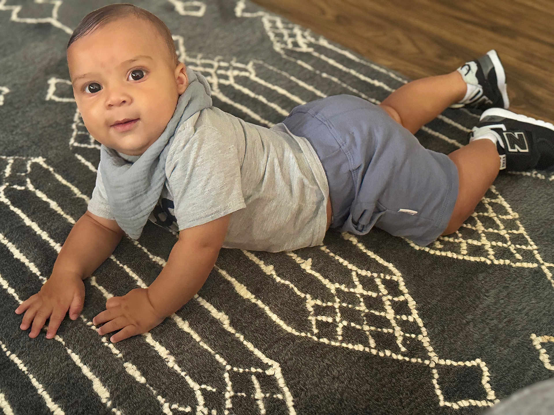Uriah joined the competition — help win amazing prizes! baby, child, infant, floor, rug, pattern, clothing, shorts, shirt, socks, sneakers, indoor, person, cute, looking_at_camera, hands, head, eyes, skin, expression