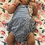 baby, infant, child, romper, headband, blue_bow, blanket, floral_pattern, sock, lying_down, pacifier, hand_in_mouth, cute, indoors, soft_texture, cozy, skin, expression, comfortable, clothing