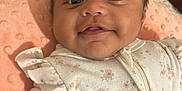 Angie joined the competition — help win amazing prizes! baby, infant, smile, face, onesie, floral_pattern, blanket, soft_texture, cute, child, portrait, indoors, warm_lighting, resting, cozy, closeup, young, happy, skin, expression