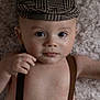 baby, child, face, hat, suspenders, skin, portrait, infant, cute, expression, lying_down, looking_at_camera, indoors, soft_light, texture, blanket, closeup, one_person, headwear, human