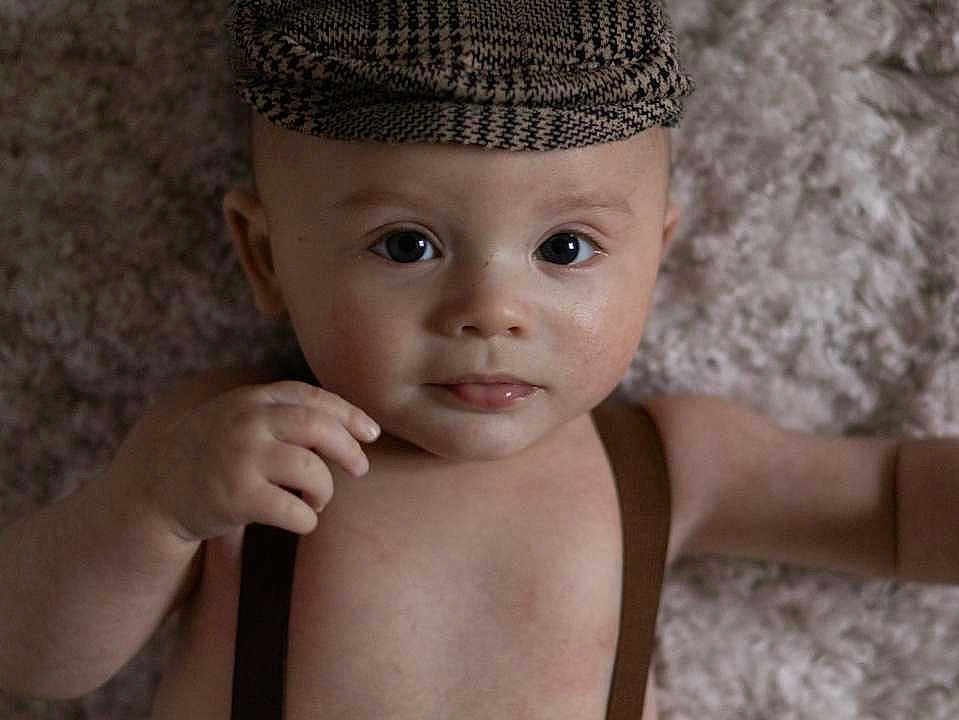Mylan participe au concours pour gagner de l'argent avec cette photo : baby, child, face, hat, suspenders, skin, portrait, infant, cute, expression, lying_down, looking_at_camera, indoors, soft_light, texture, blanket, closeup, one_person, headwear, human